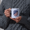 Taza blanca con diseño de escudo deportivo en rojo, blanco y azul del Club Atlético de Madrid sociedad anónima deportiva
