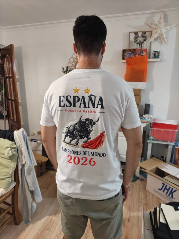 Hombre con camiseta blanca de España Campeones del Mundo 2026, diseño trasero de toro bravo y capote rojo.